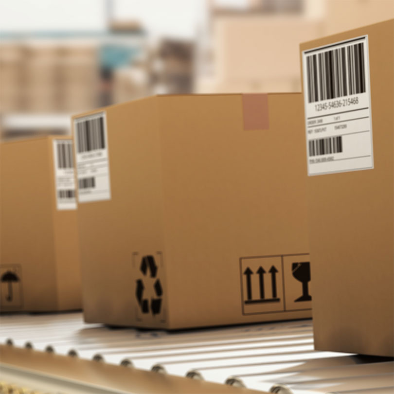 Three carboard boxes with bar codes on a conveyor belt.