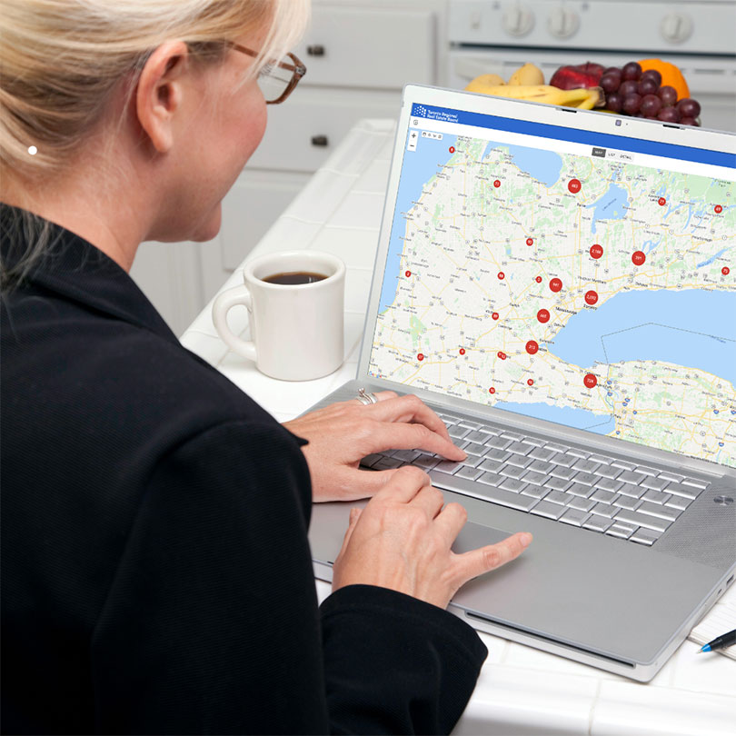 A woman looking at a map on a laptop with red markers.