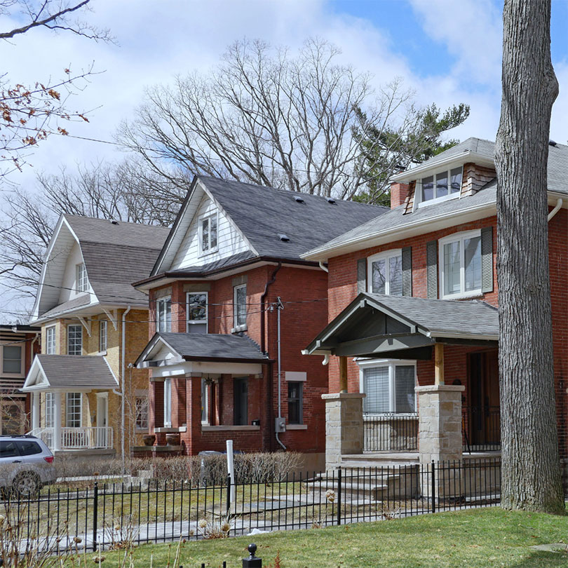 Three detached houses on a neighborhood street.
